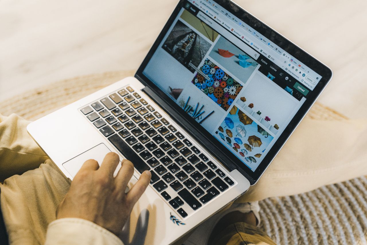 Une personne utilise un ordinateur portable pour parcourir des sites de photos de stock. Travail indépendant dans un cadre chaleureux.