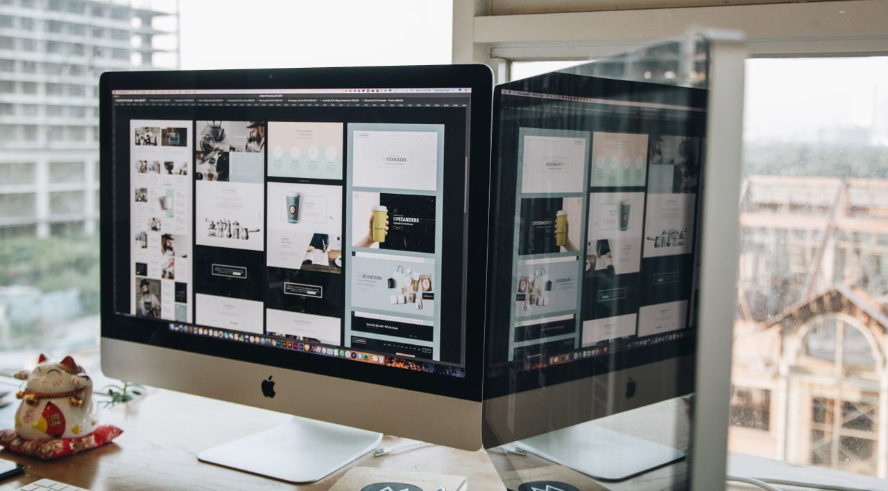 Two monitors on a desk, highlighting web design in a contemporary office environment.